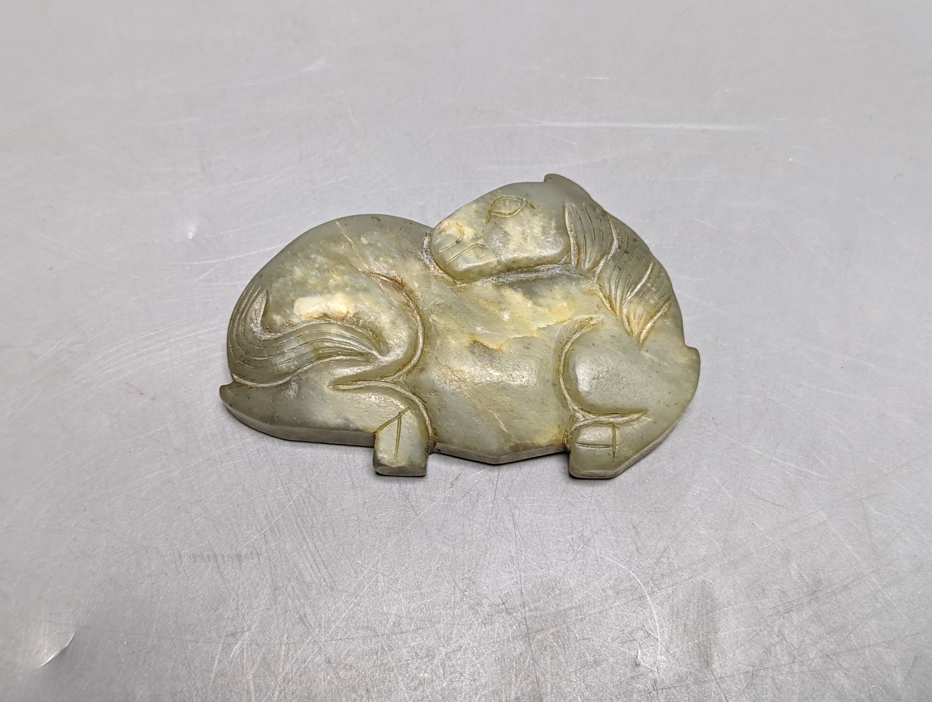 A Chinese jade carving of a resting horse, 7cm and a Himalayan cast gilt-bronze mount